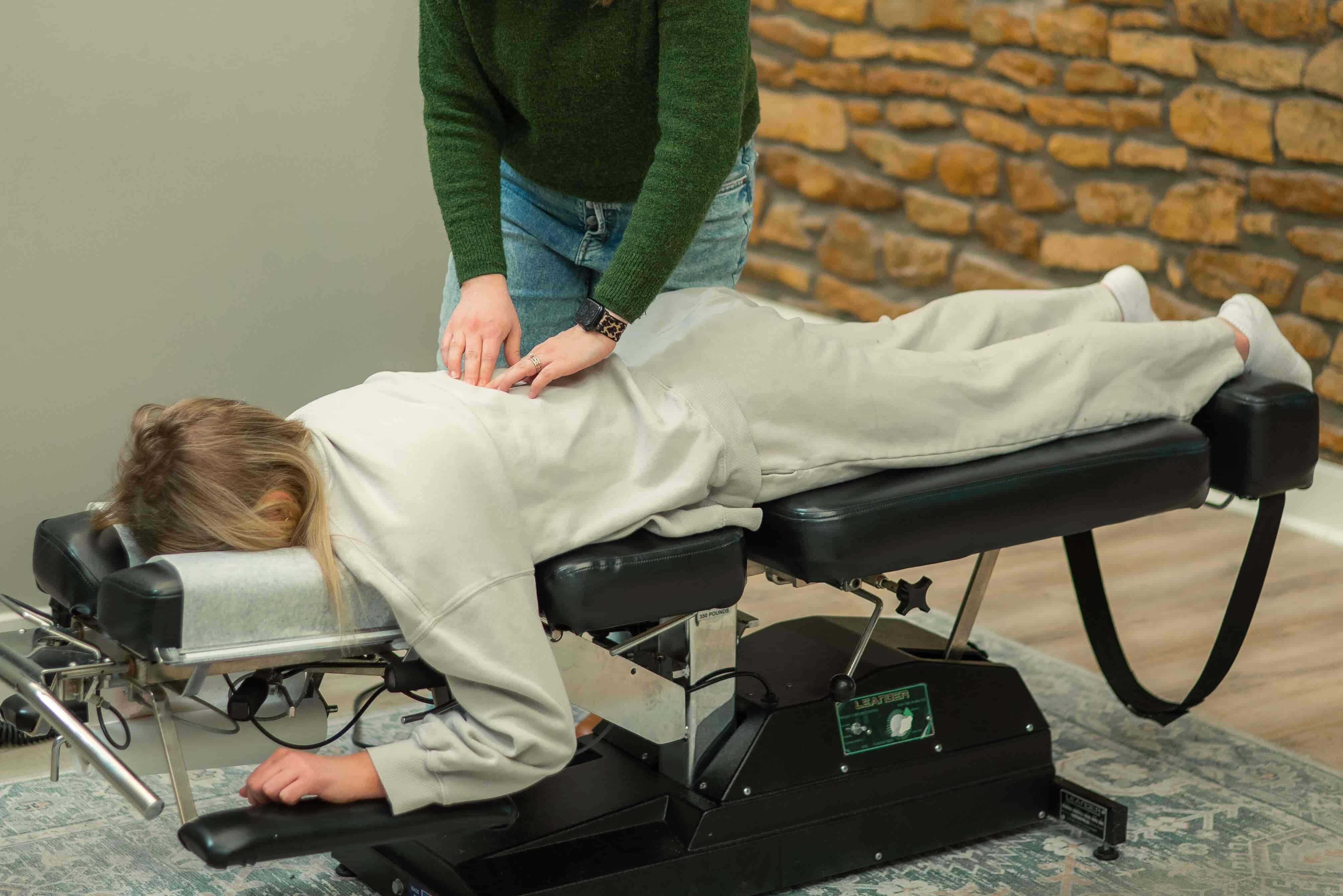 Dr. Maggie Hunsicker adjusting Topeka patient while babies play safely - welcoming family-friendly chiropractic environment